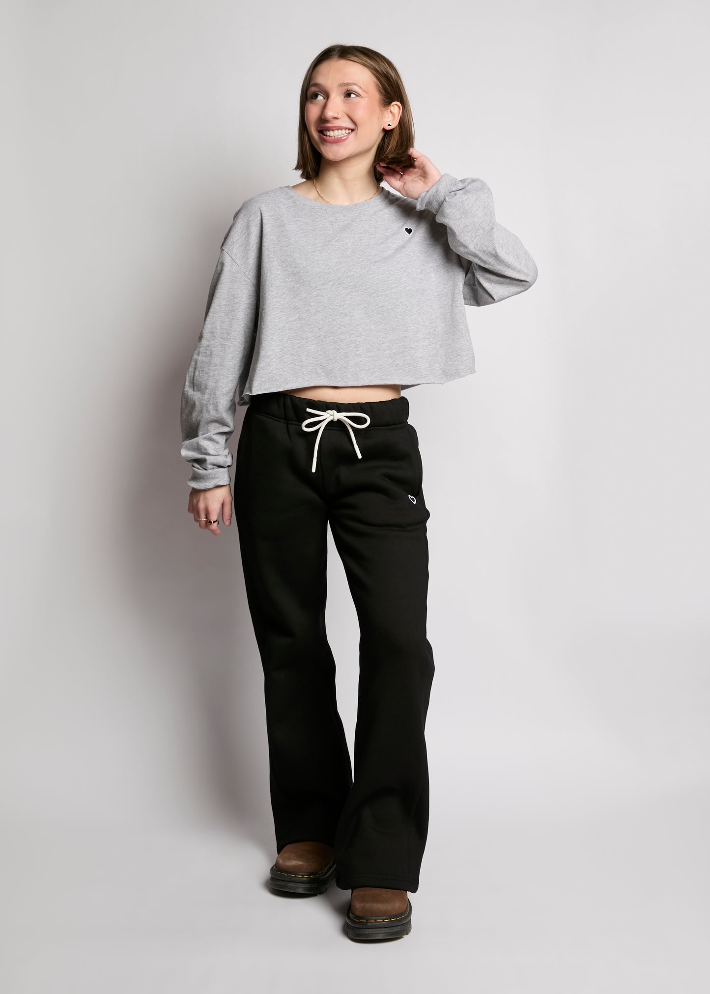 Person wearing a gray cropped sweatshirt and black pants on a plain background