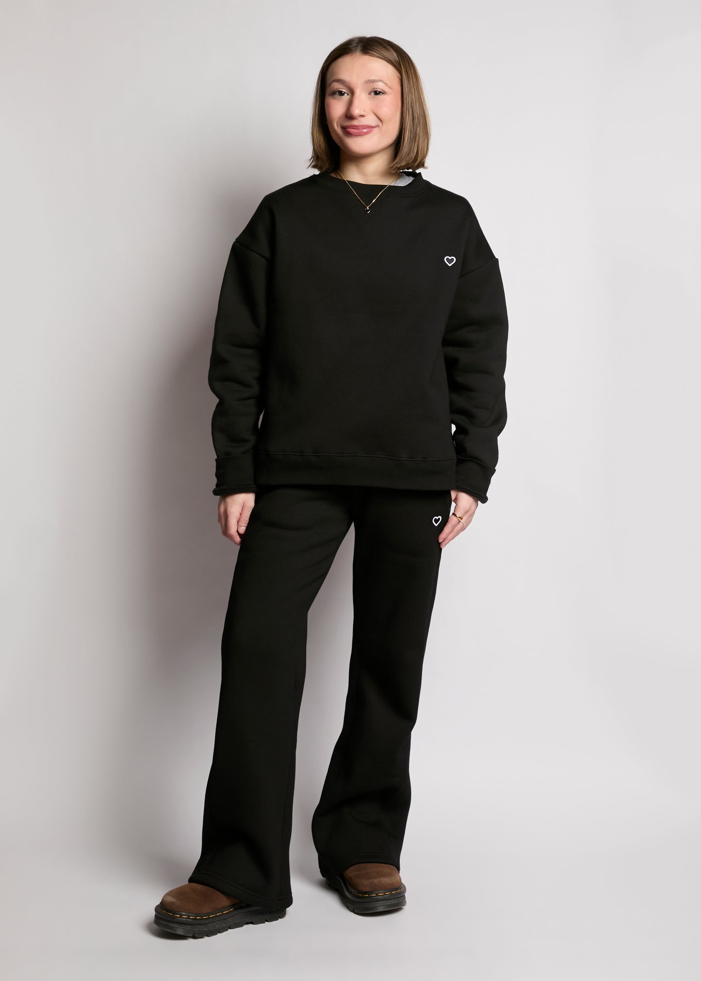 Person wearing a black sweatshirt and pants on a plain background