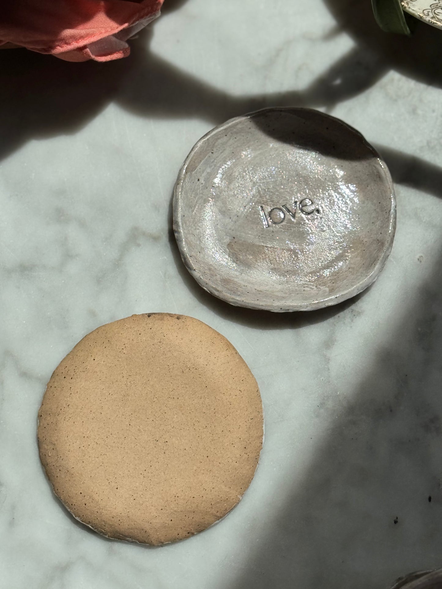 Two ceramic bowls, one with 'love' engraved, on a marble surface.