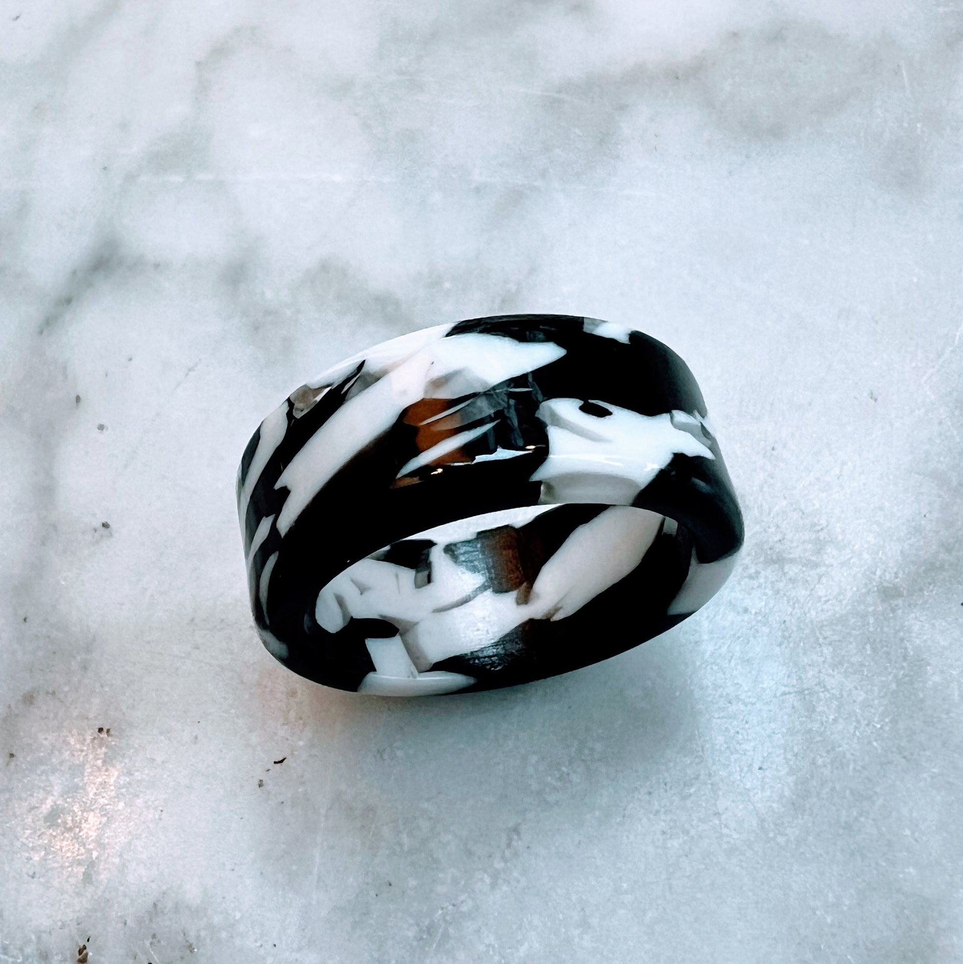 A candy ring with a black and white licorice pattern, placed on a marble surface.