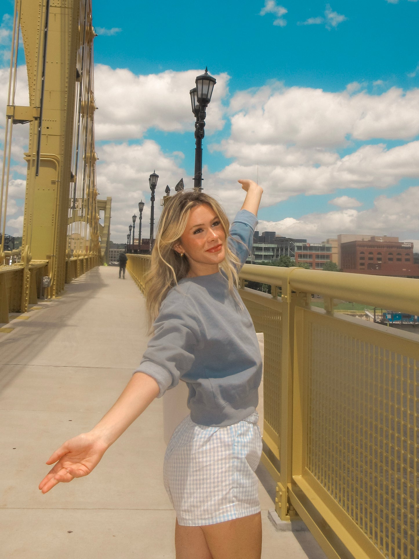 Woman posing on a bridge with a cityscape in the background
