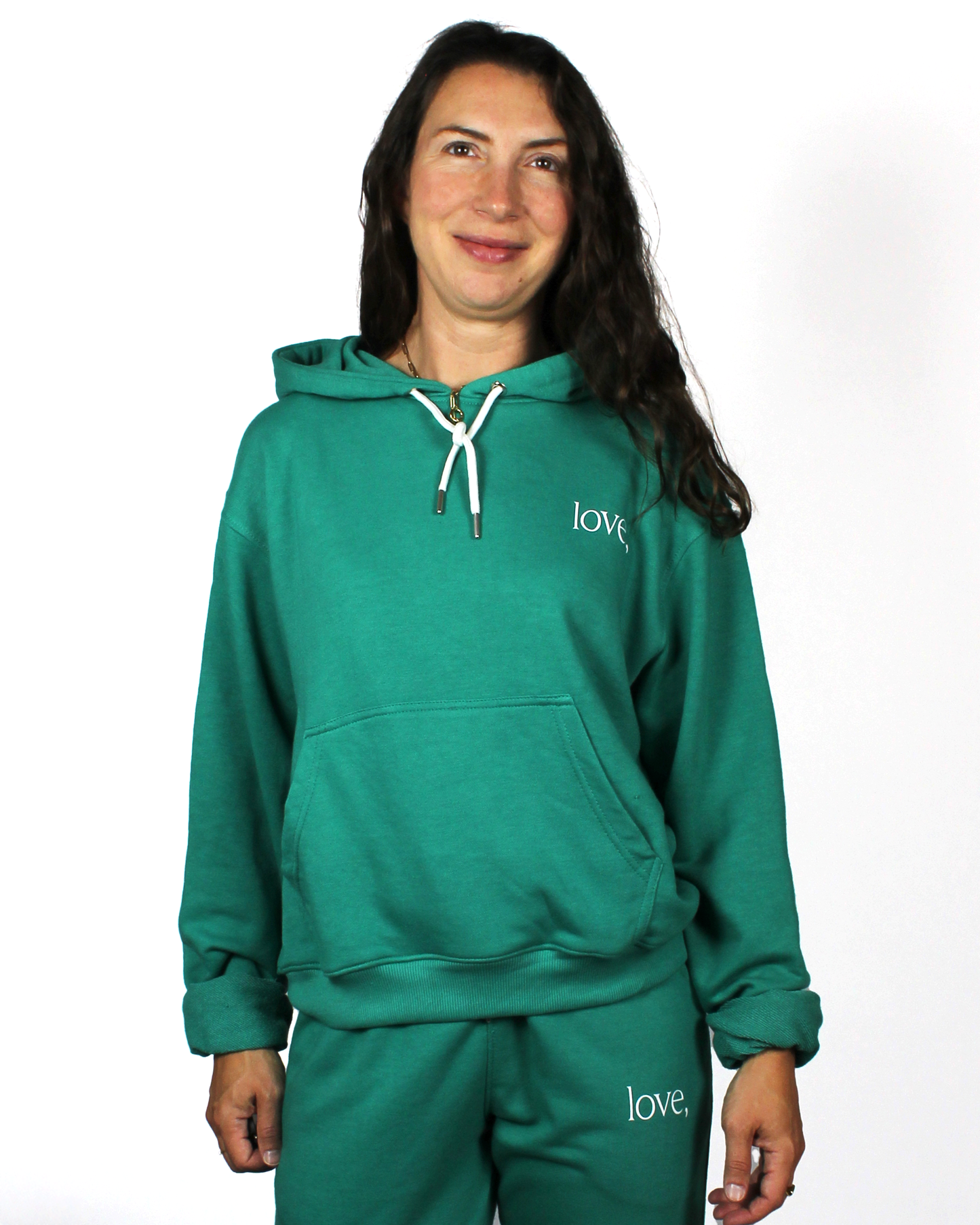 Person wearing a teal hoodie and pants with 'love,' branding on a white background
