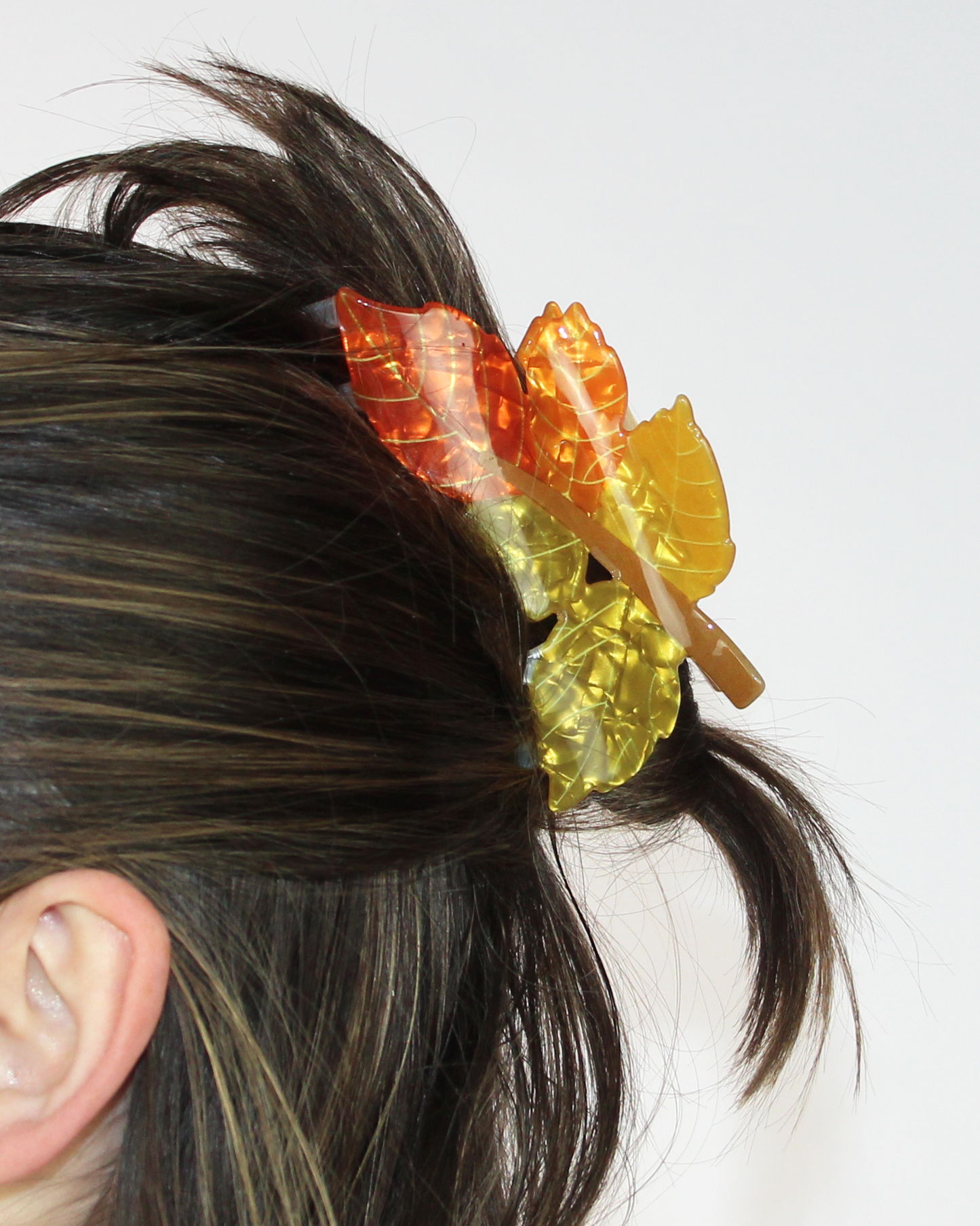 Close-up of a person's hair with colorful leaf-shaped hair ties.