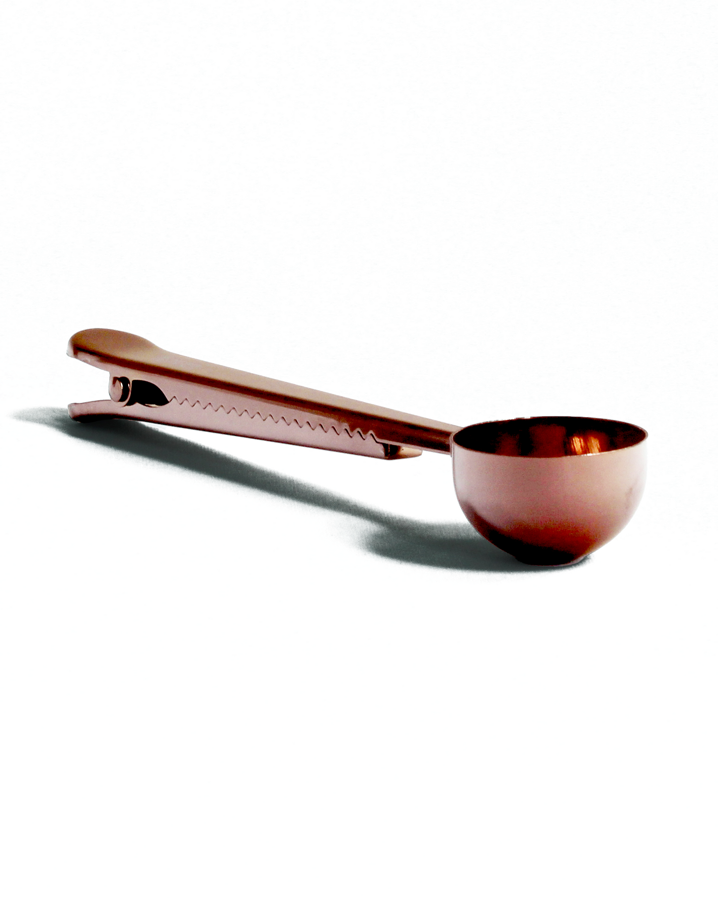 Copper-colored measuring spoon on a white background