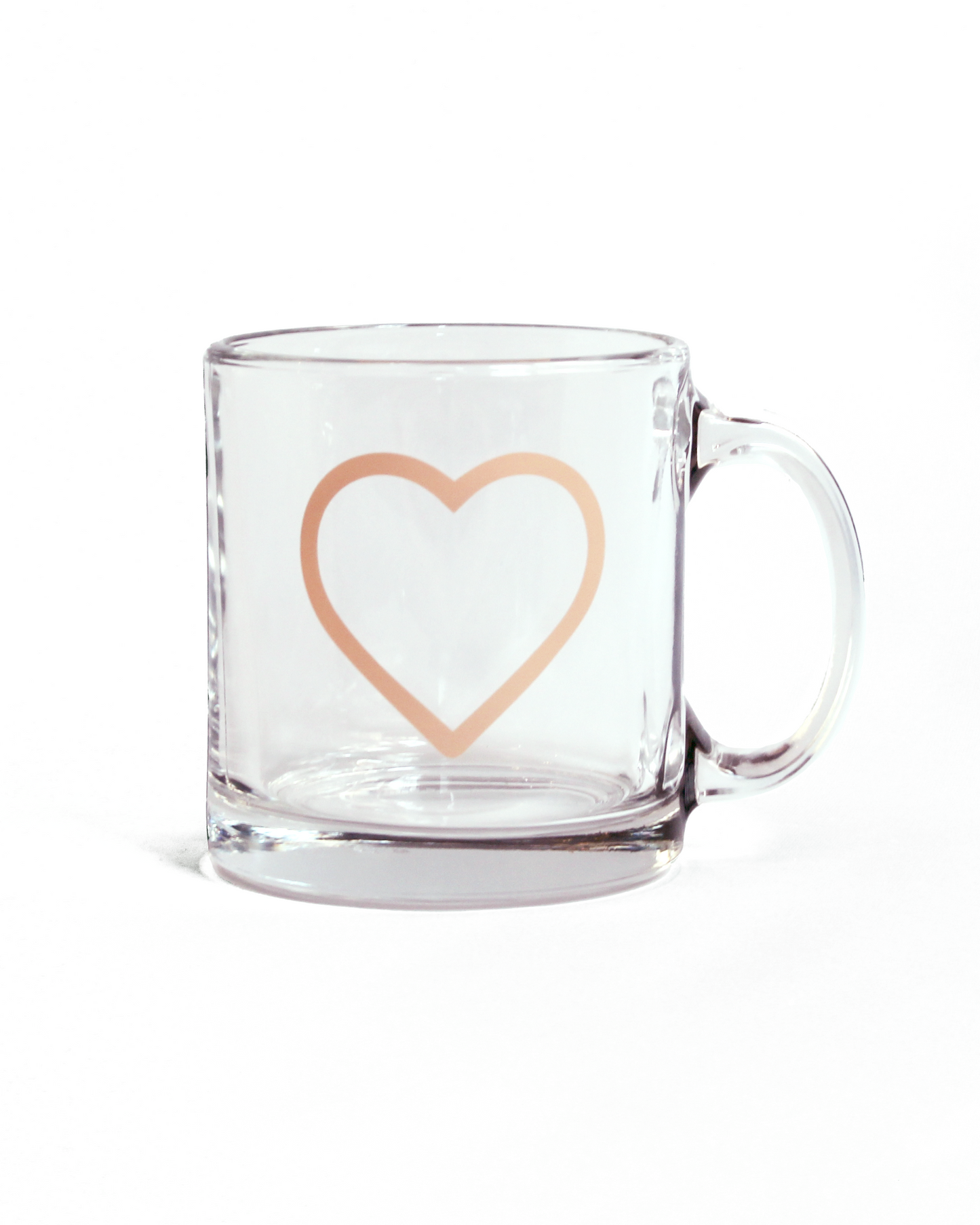 Clear glass mug with a coral pink heart design on a white background