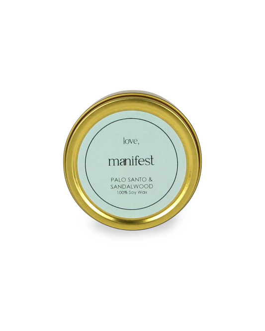 Manifest candle tin with gold lid and green label on a white background