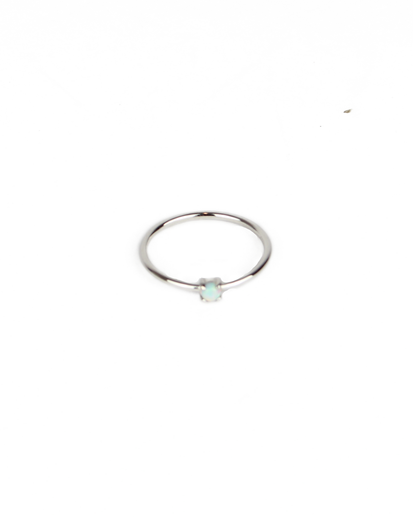 Silver ring with a small green gemstone on a white background