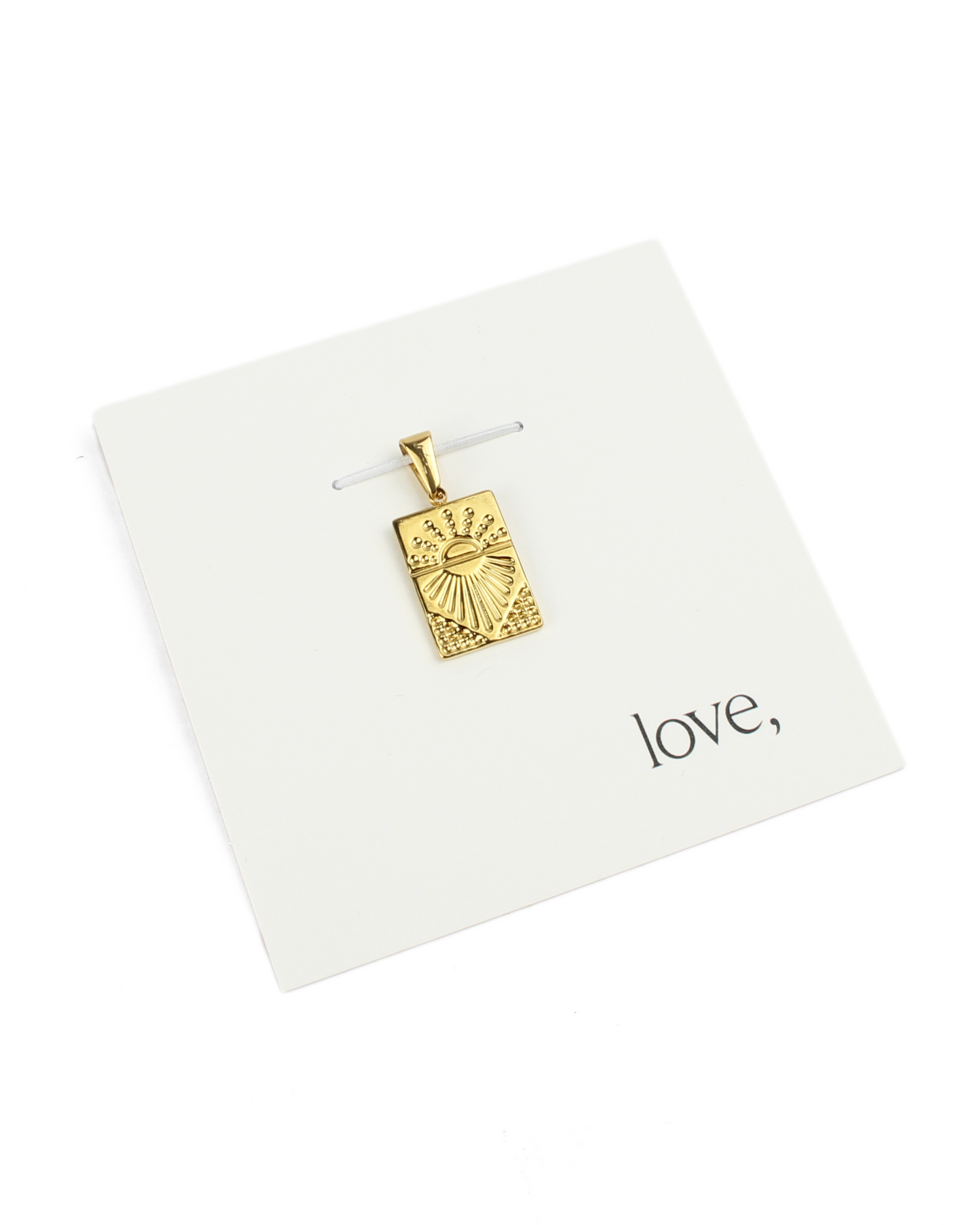 gold charm on a card on a white background