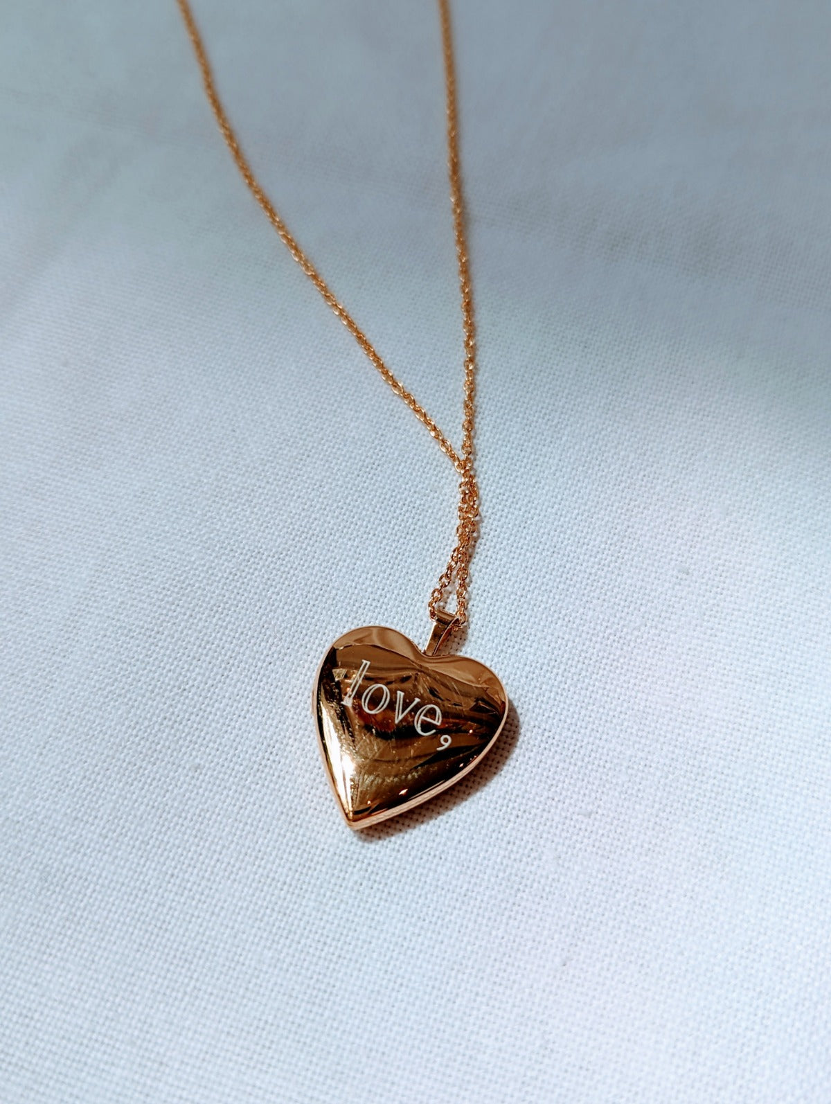 A gold-plated sterling silver heart-shaped locket on an 18-inch chain, with the word 'love' engraved on it.