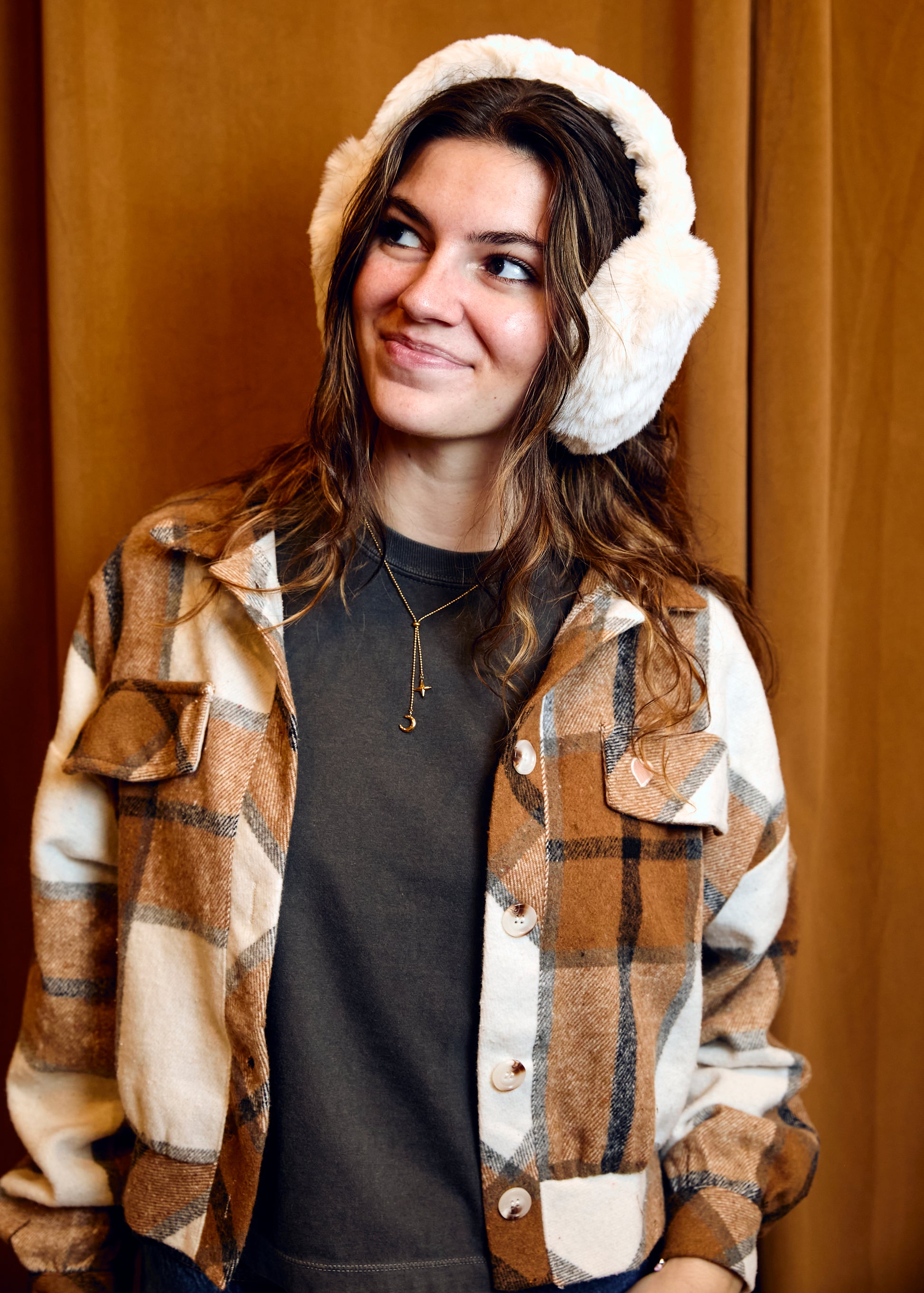 Person wearing a plaid shirt over a dark top with a white hooded garment on a plain background