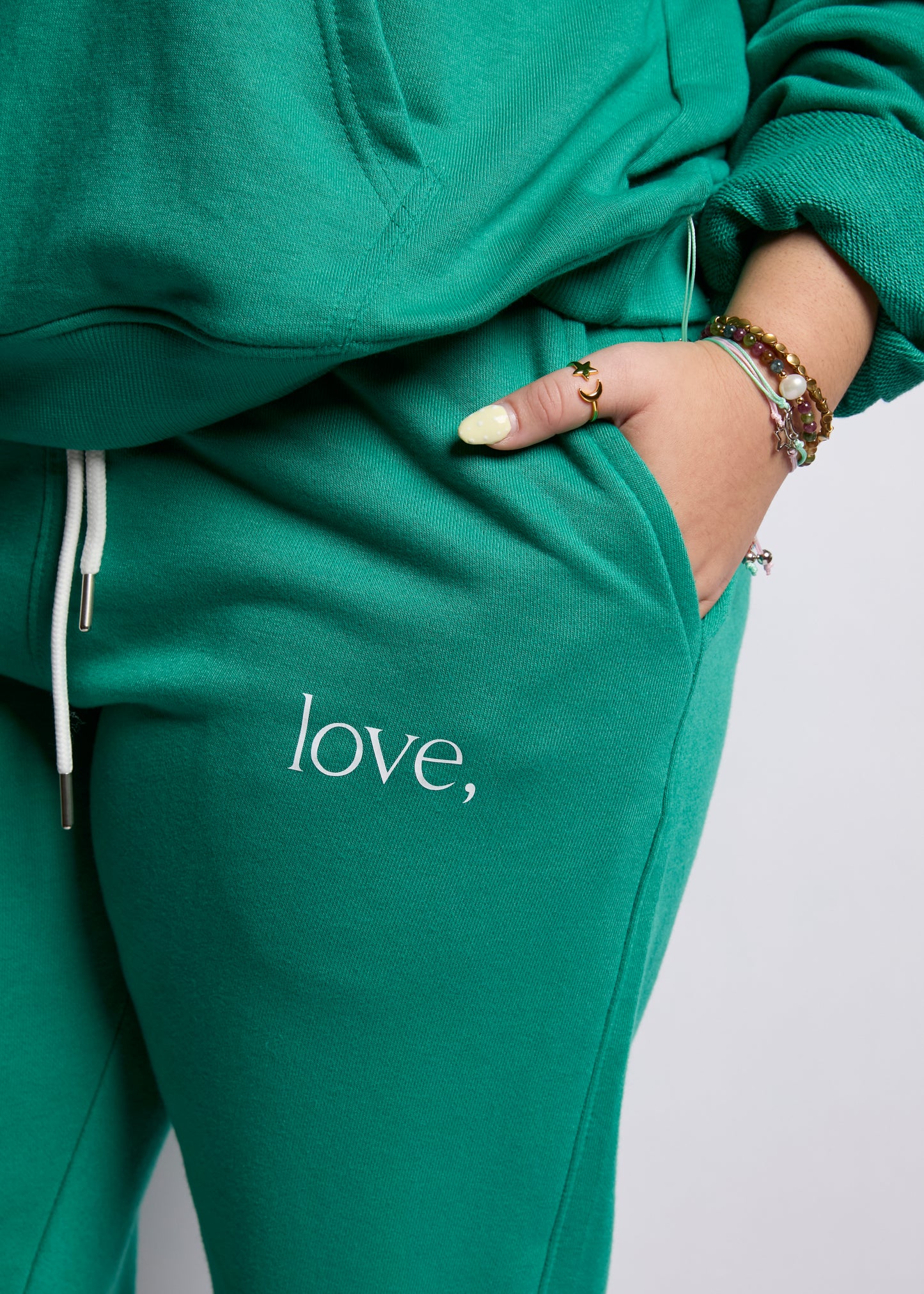 Green sweatpants with 'love,' text on a plain background