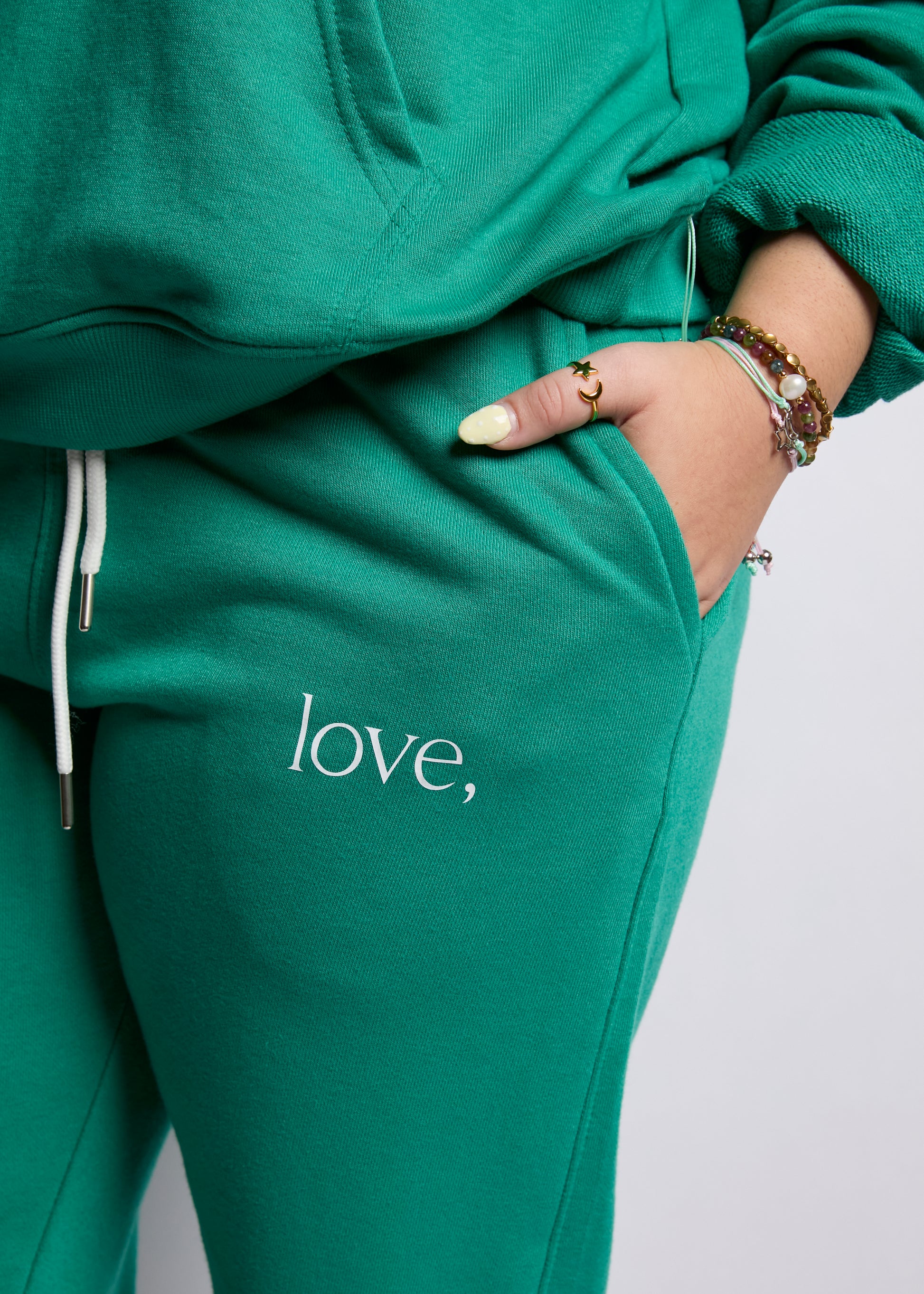 Green sweatpants with 'love,' text on a plain background