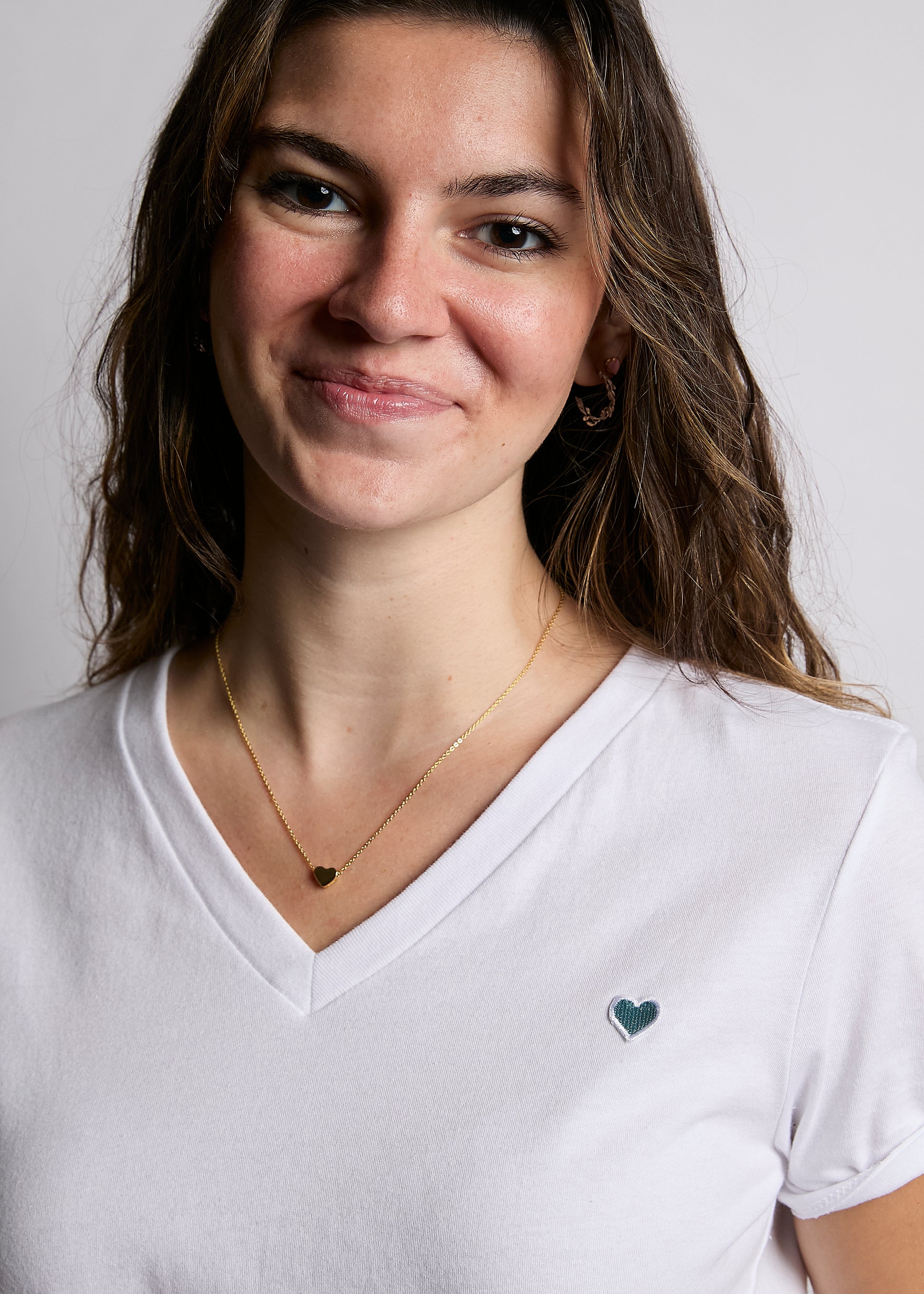 Woman wearing a white t-shirt with a heart design on a plain background