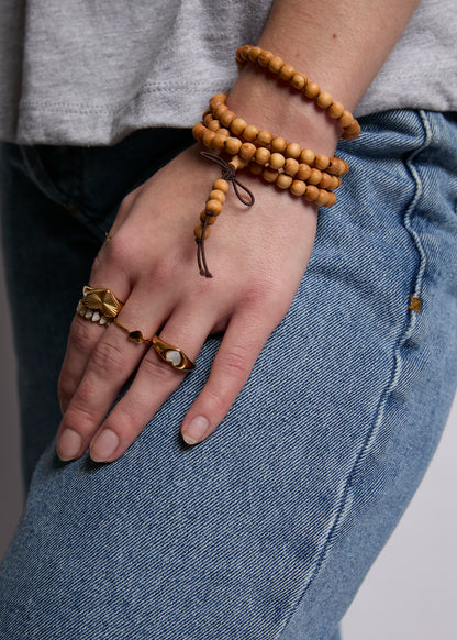 Hand wearing multiple bracelets and rings with a blurred background