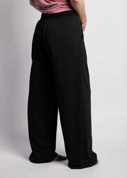 Back view of wide leg black sweatpants with pink tee