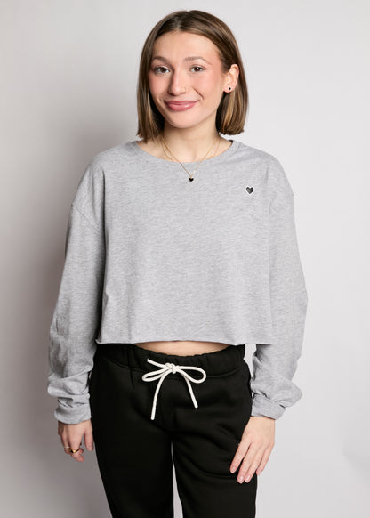 Person wearing a gray cropped sweatshirt with heart details on a plain background