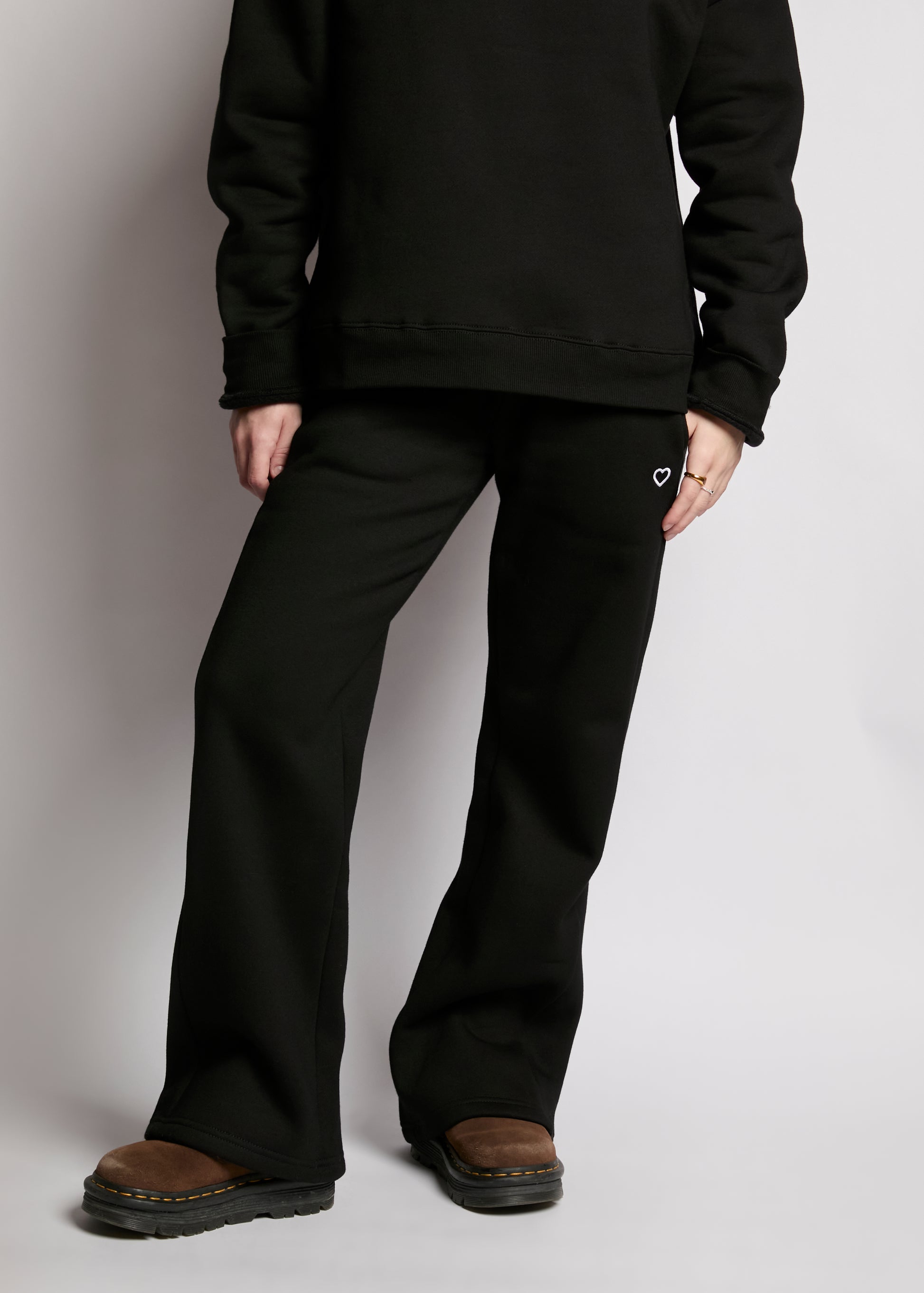Person wearing a black hoodie and black pants on a plain background
