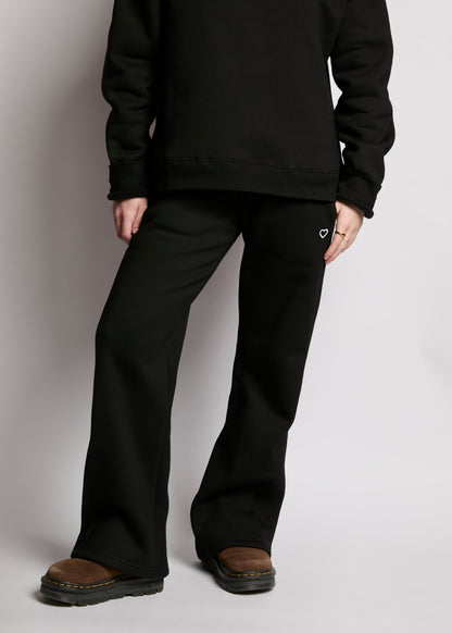 Person wearing a black hoodie and black pants on a plain background