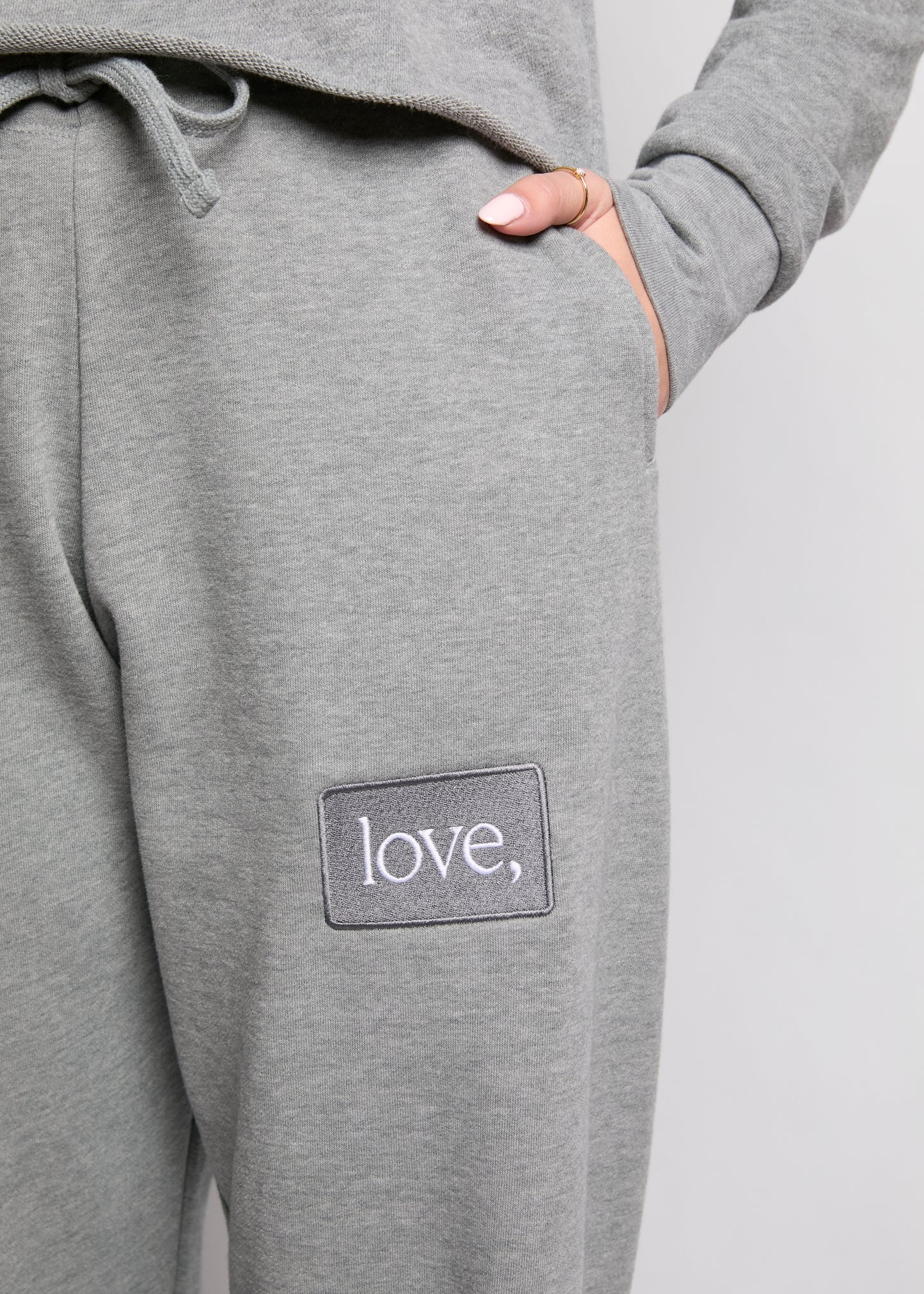 Gray sweatpants with 'love' patch on a plain background