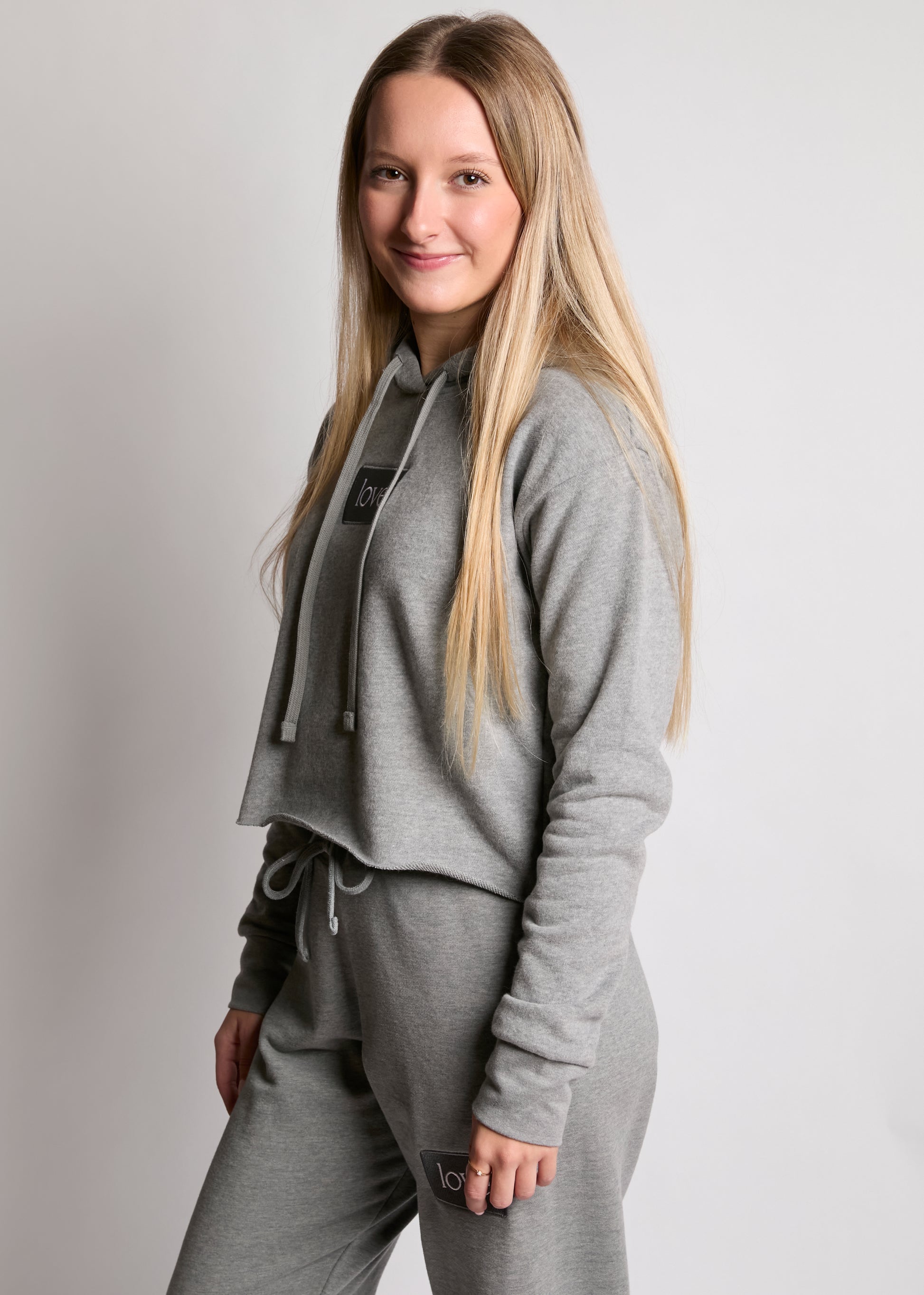 Woman wearing a gray tracksuit against a plain background