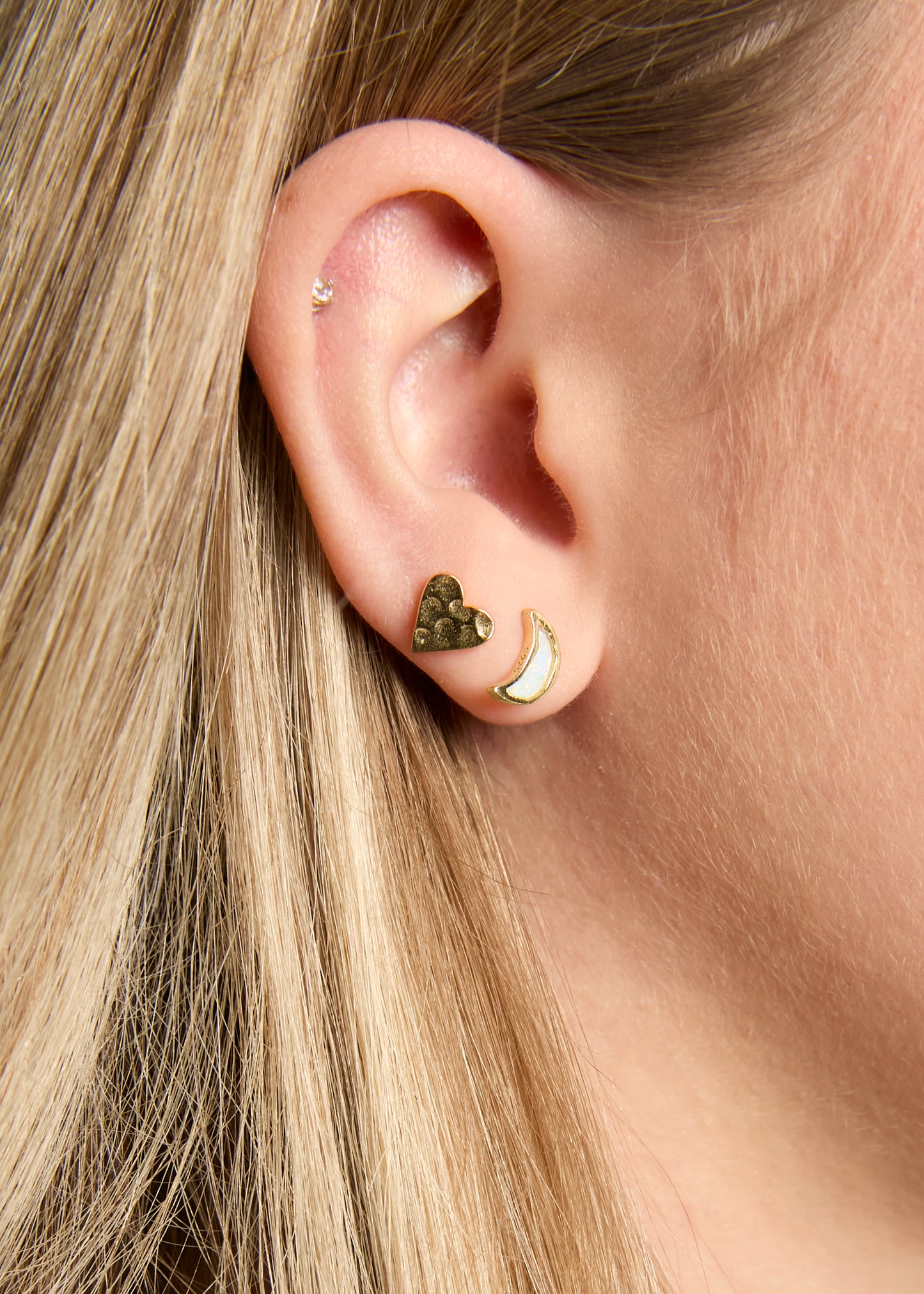Close-up of an ear with gold and bronze earrings