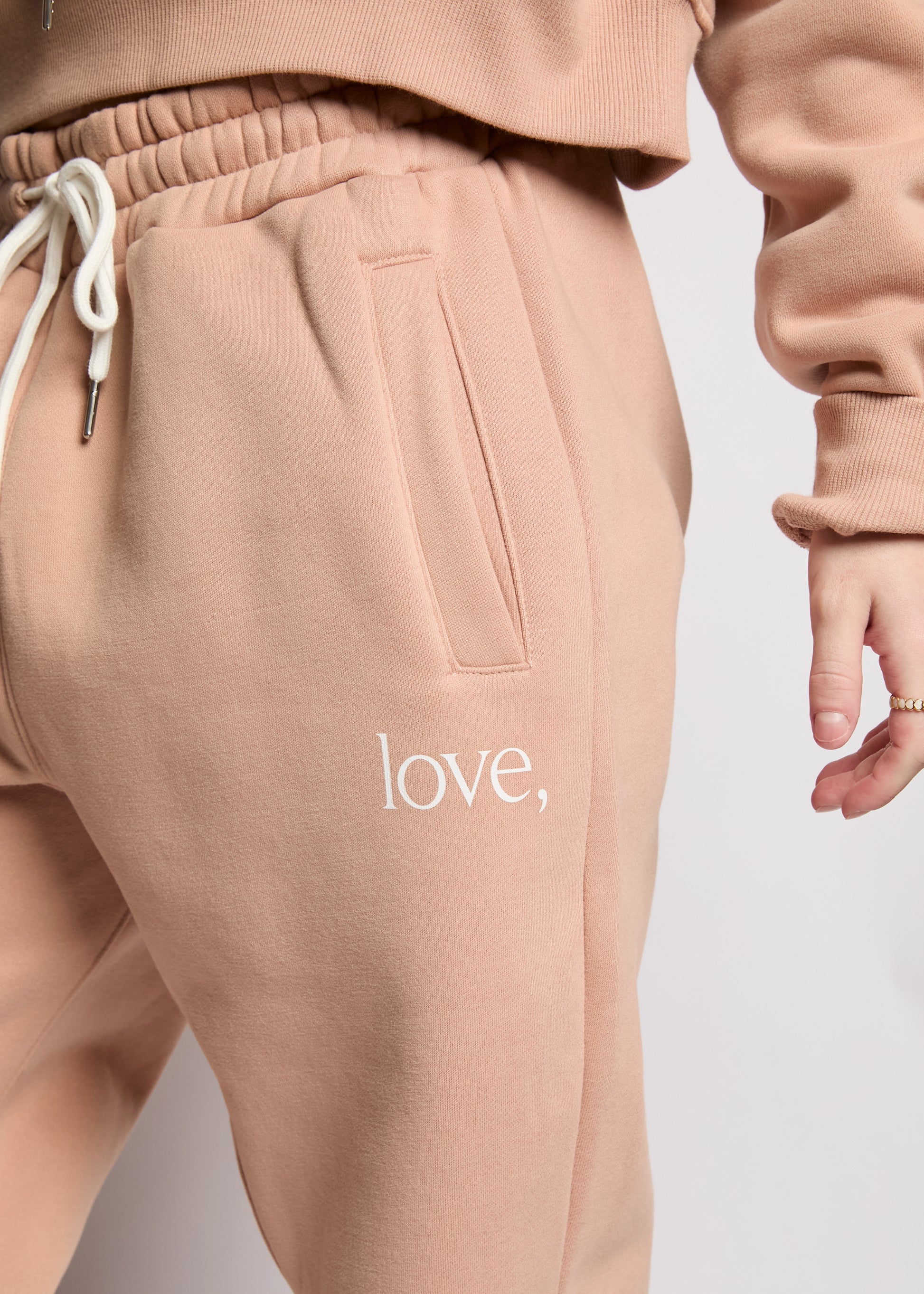 Beige sweatpants with 'love' text on a plain background