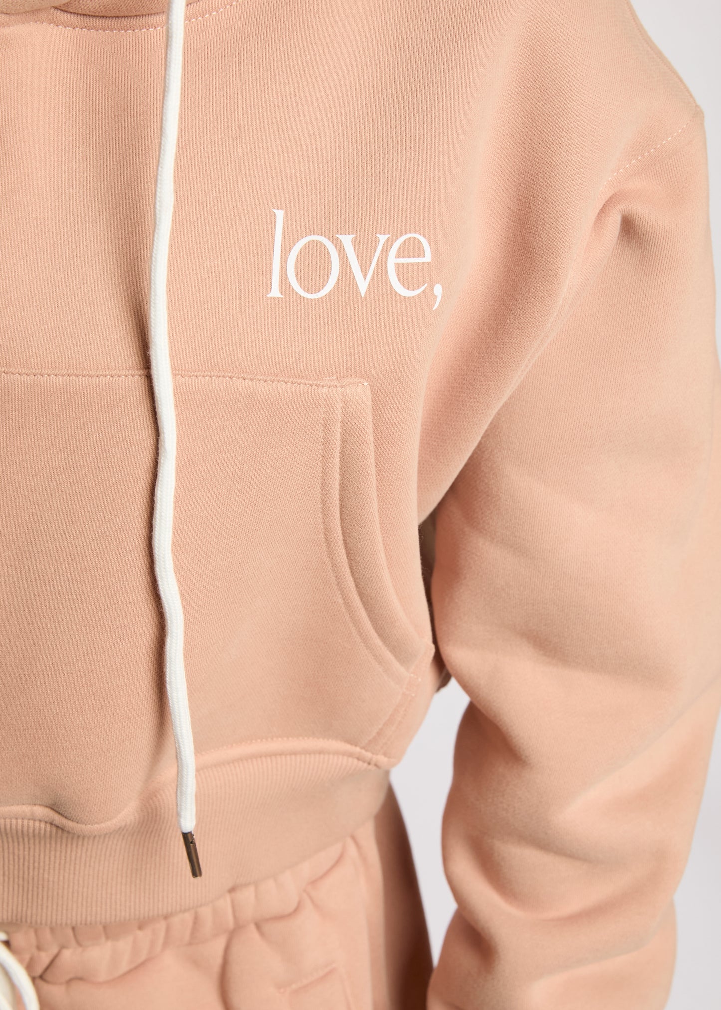 Beige hoodie with 'love,' text on a light gray background