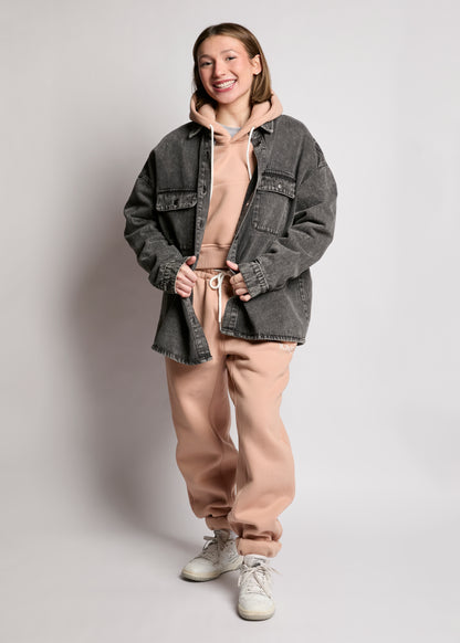 Person wearing a gray jacket over a beige hoodie and pants on a plain background