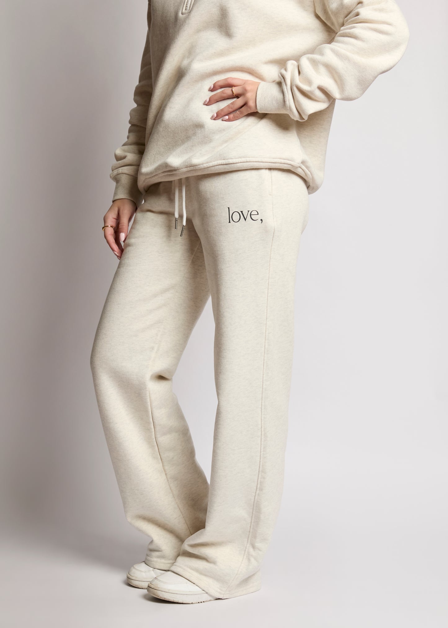 Person wearing a cream-colored hoodie and pants with 'love' text on a light gray background