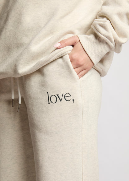 Beige hoodie and pants with 'love,' text on a plain background