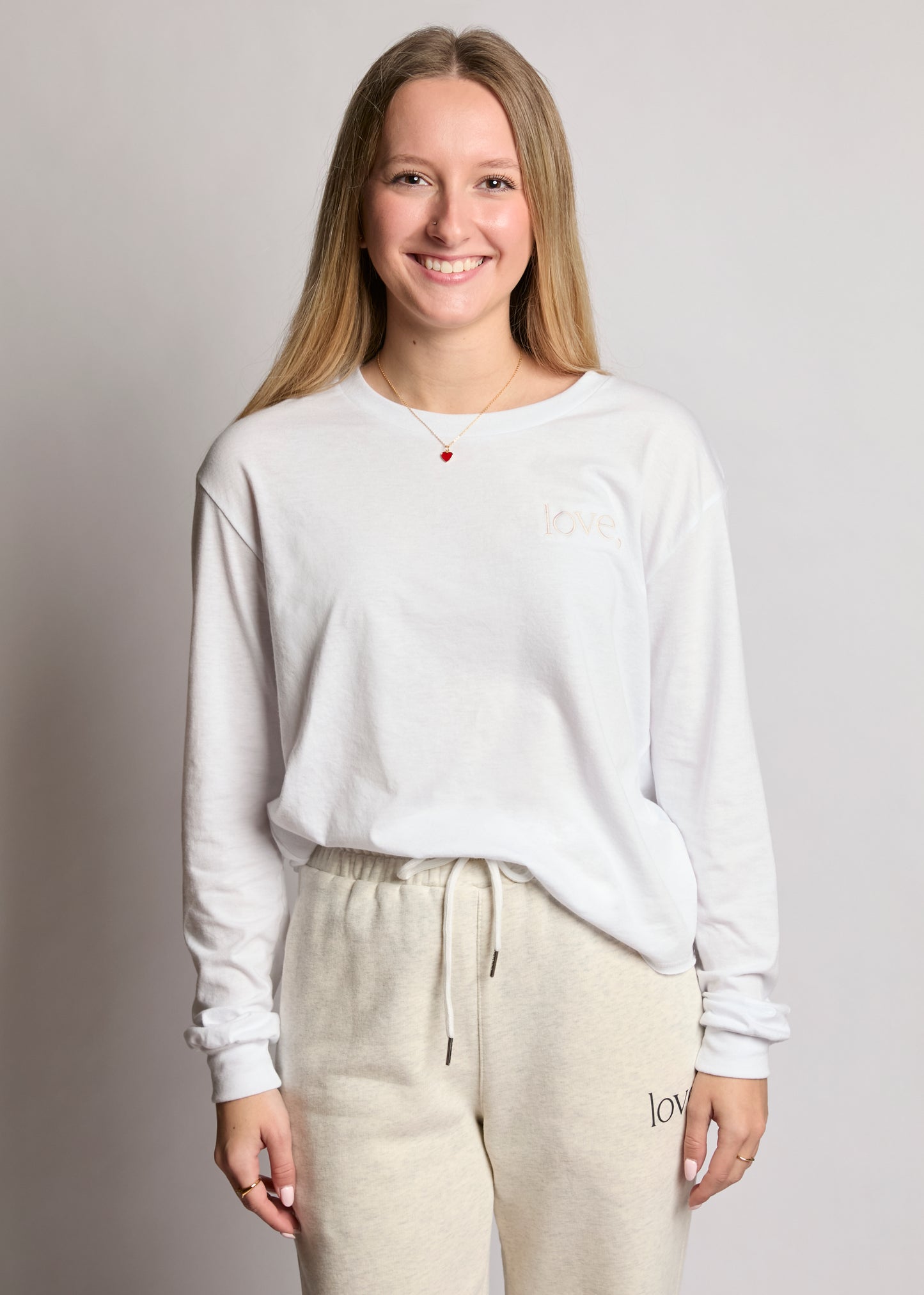 Person wearing a white sweatshirt and beige pants on a plain background