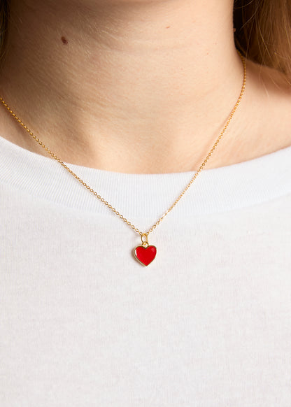 Gold necklace with a red heart pendant on a white background