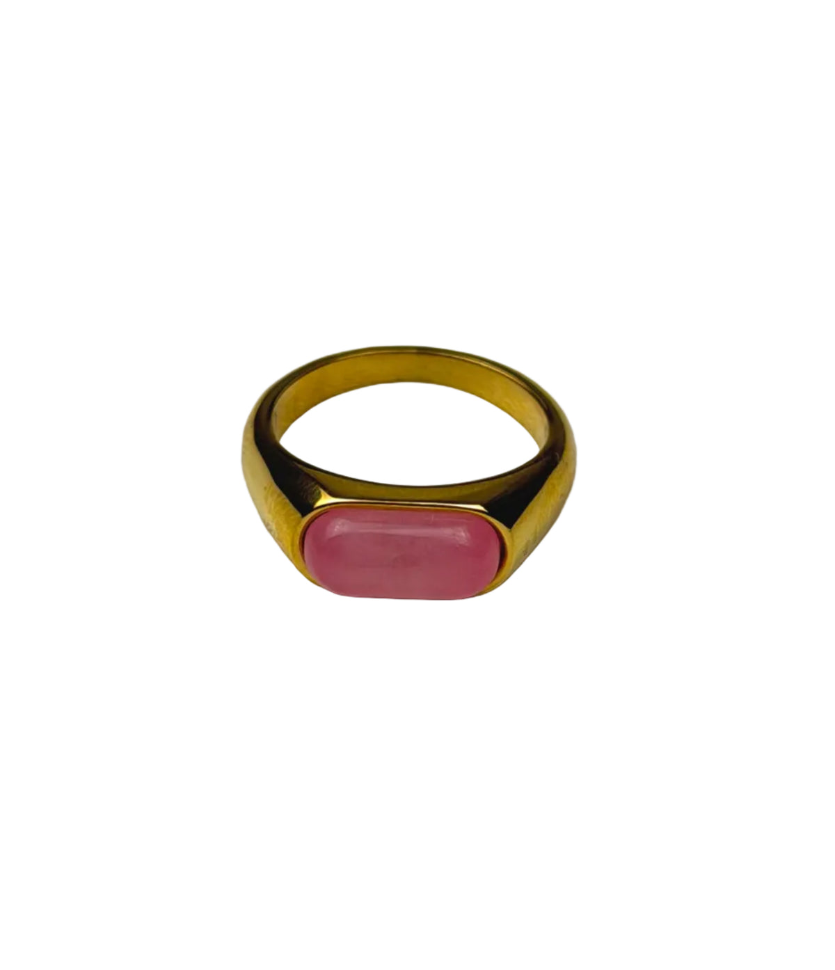 A gold signet ring with an oval pink cabochon gemstone, displayed on a light gray textured surface.