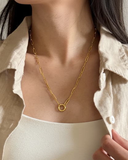 Gold chain necklace worn by a person with a neutral background