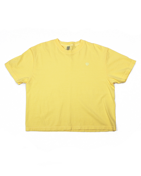 Yellow tee with a heart patch on a white background.