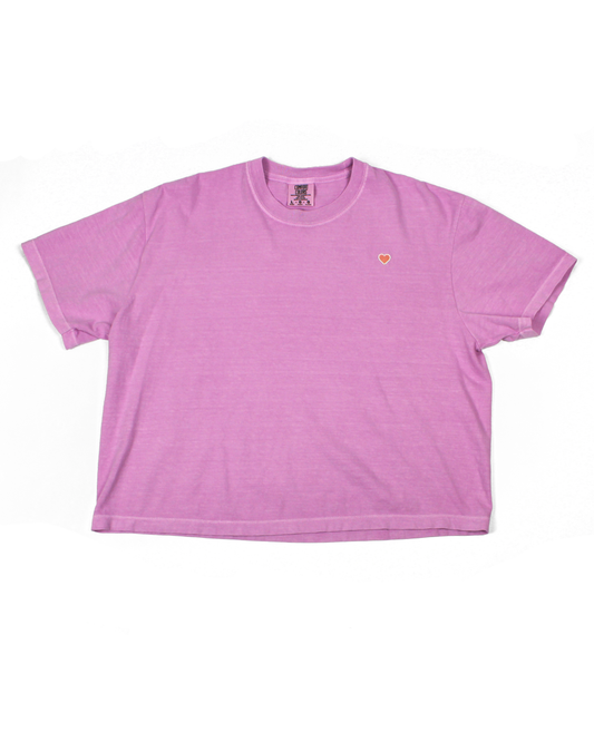 Pink tee with heart patch on a white background