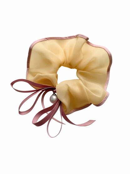 Yellow scrunchie with pink ribbons on a white background