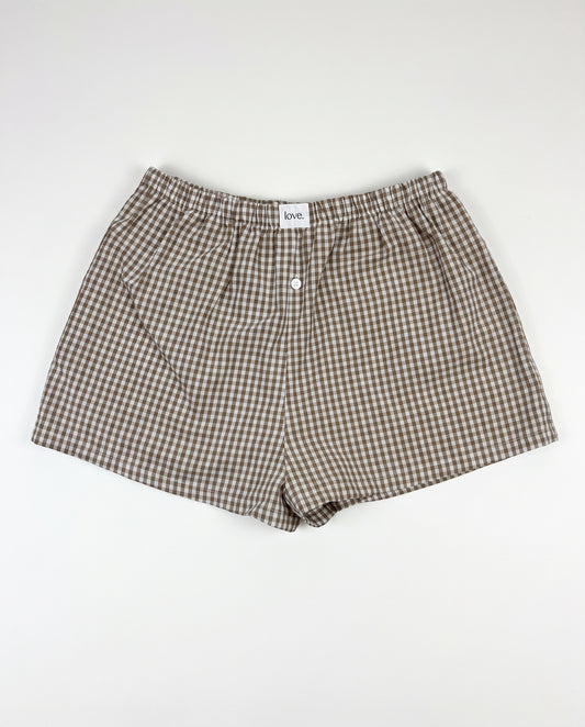 Brown and beige gingham check boxer shorts with an elastic waistband and front button closure, laid flat on a white background.