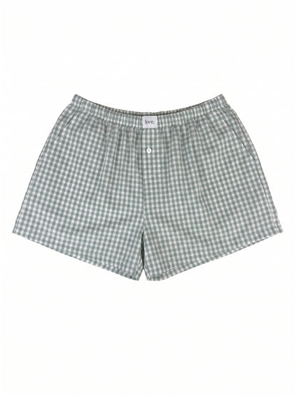 A pair of men's shorts featuring a green and white gingham check pattern, laid flat against a solid white background.
