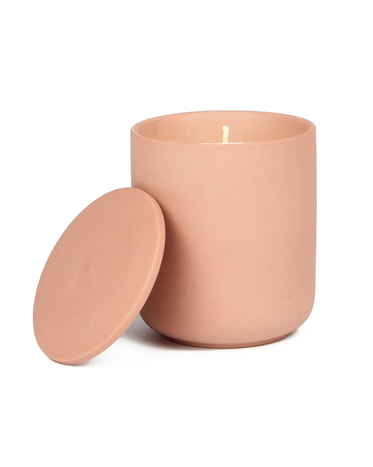Pink candle in a container with a lid on a white background