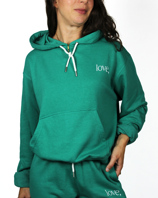 Green hoodie with 'love,' text worn by a person on a white background