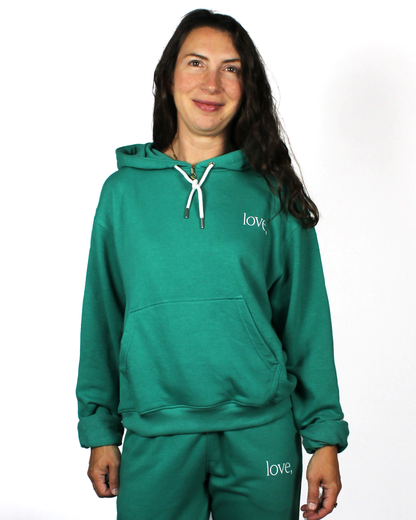Person wearing a teal hoodie and pants with 'love,' branding on a white background