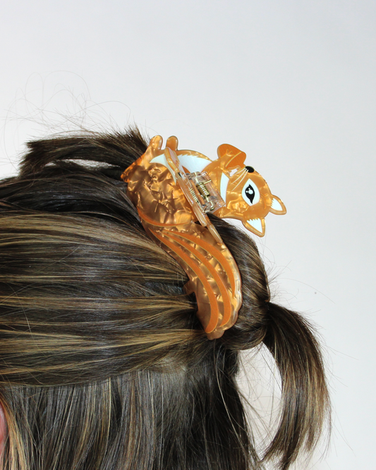 Orange hair clip on a person's hair against a white background