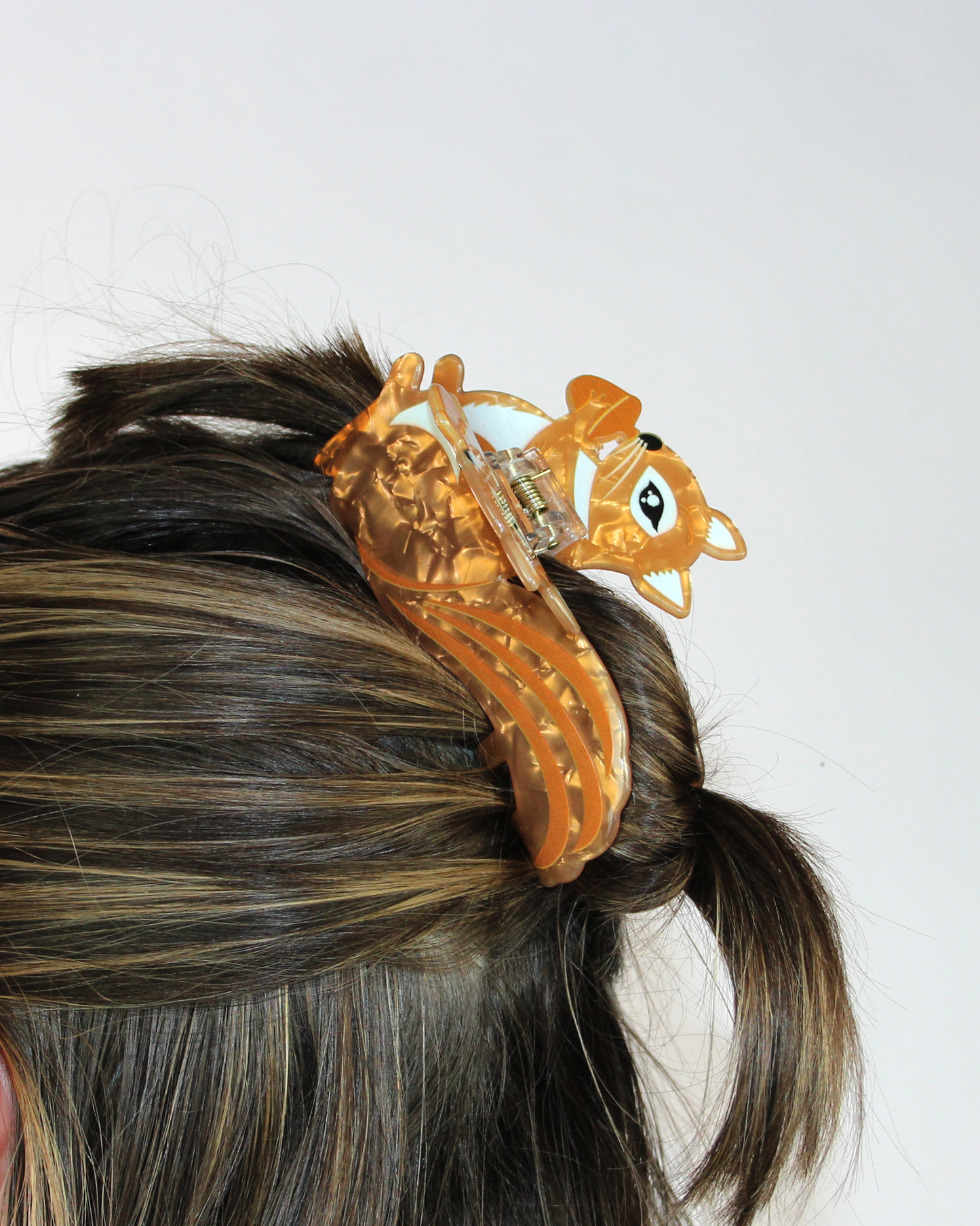 Orange hair clip on a person's hair against a white background