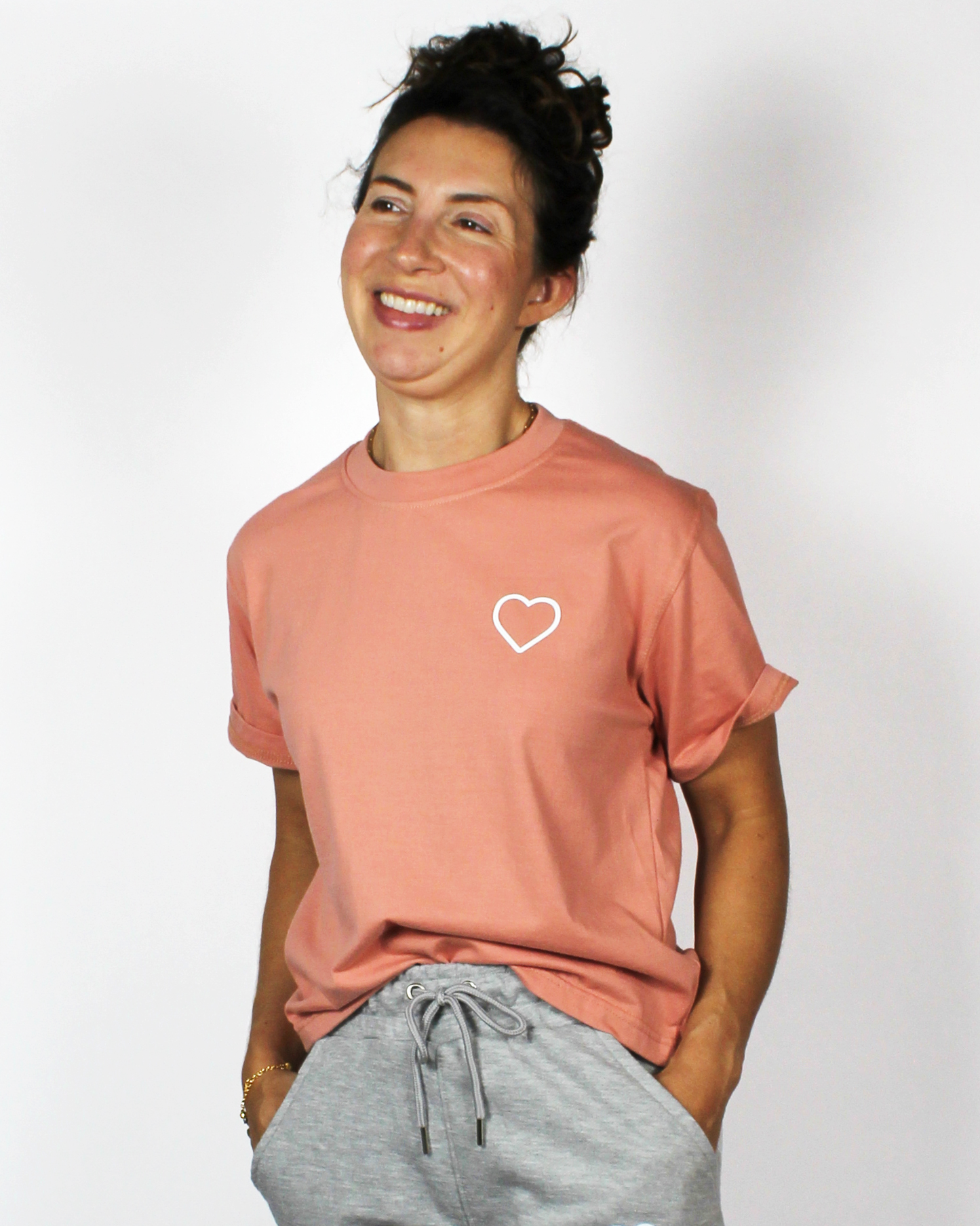 Person wearing a pink t-shirt with a heart design on a plain background