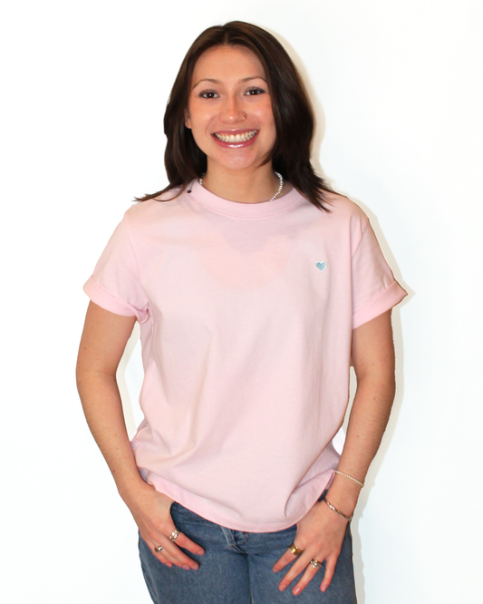 Woman wearing a light pink t-shirt with a small logo on a white background