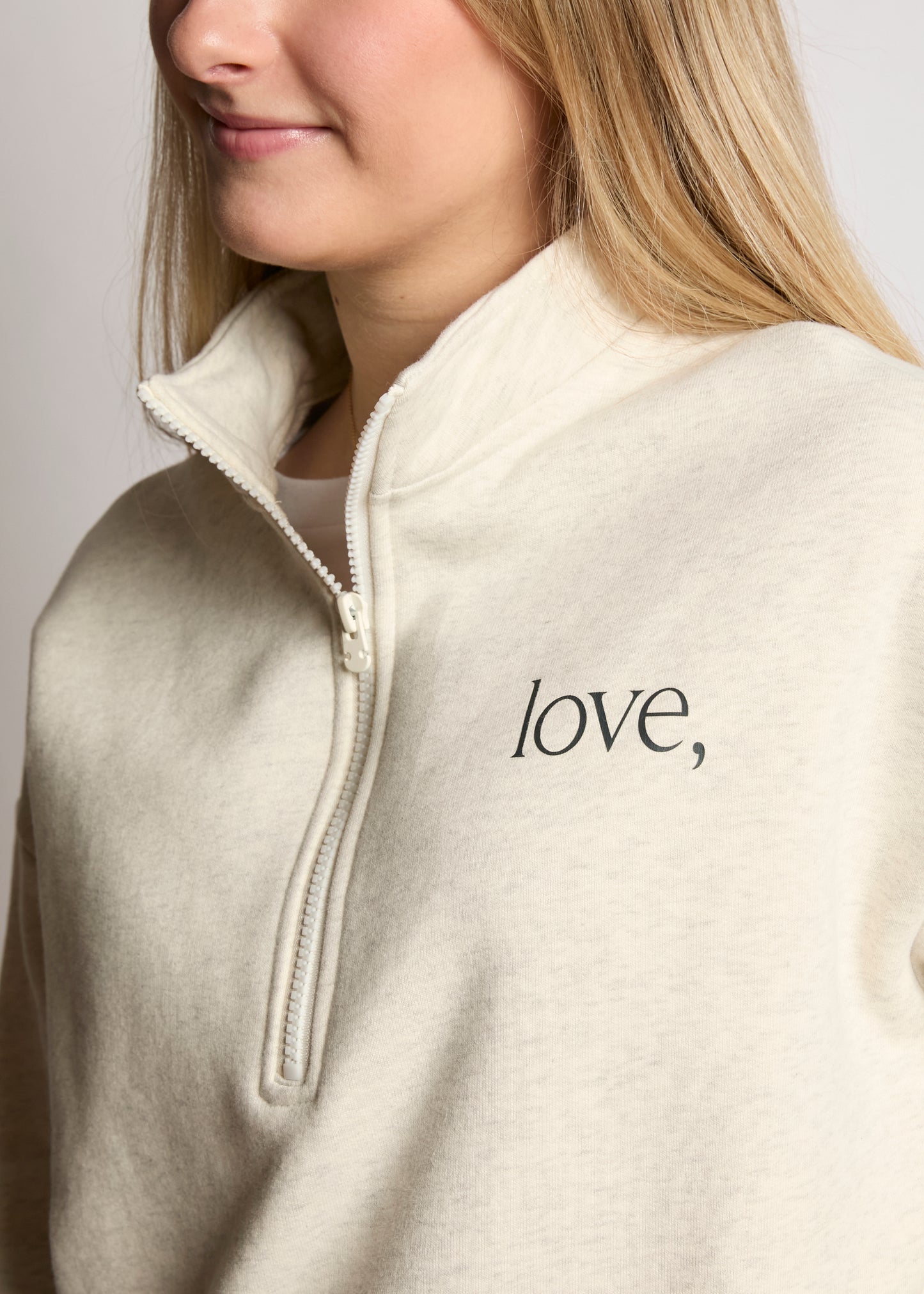 Person wearing a beige fleece jacket with 'love' text on a plain background