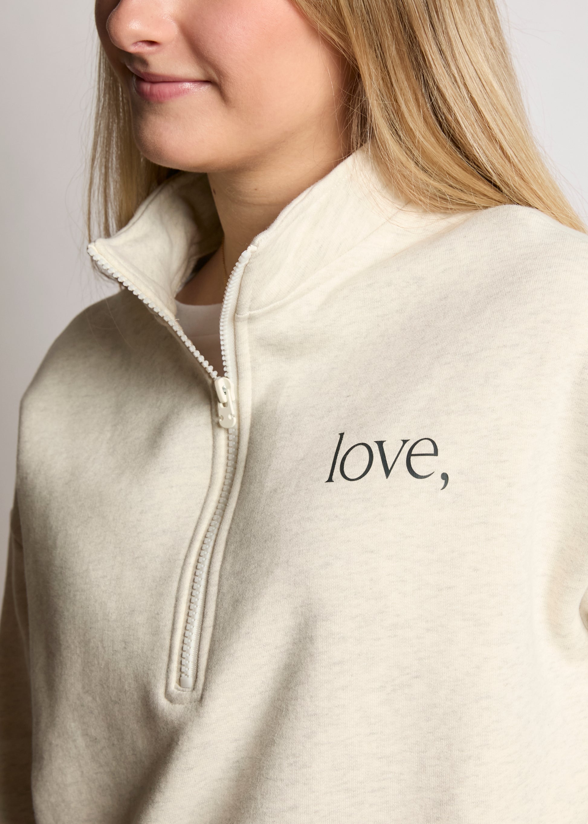 Person wearing a beige fleece jacket with 'love' text on a plain background