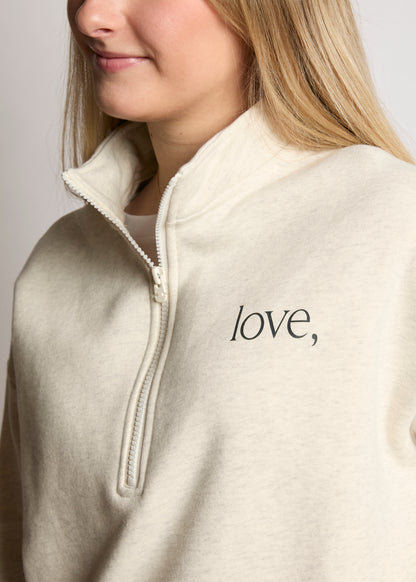 Person wearing a beige fleece jacket with 'love' text on a plain background