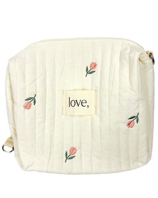 Quilted bag with floral embroidery and 'love' label on a white background